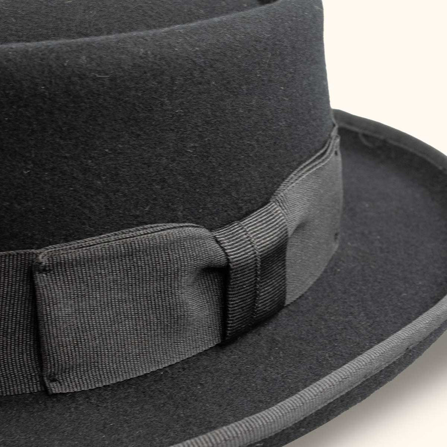 Detalle del sombrero pork pie La Nutria: cinta oscura con lazo y borde ribeteado