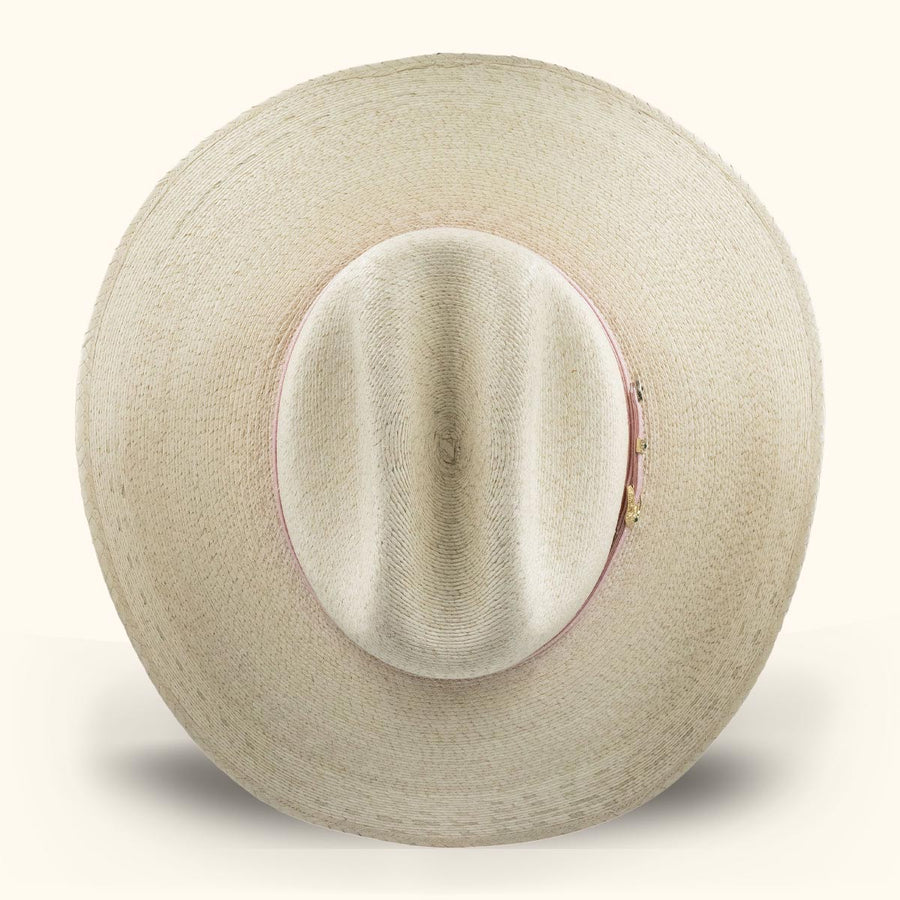 Sombrero de paja clara visto desde arriba, con cinta rosa alrededor de la copa