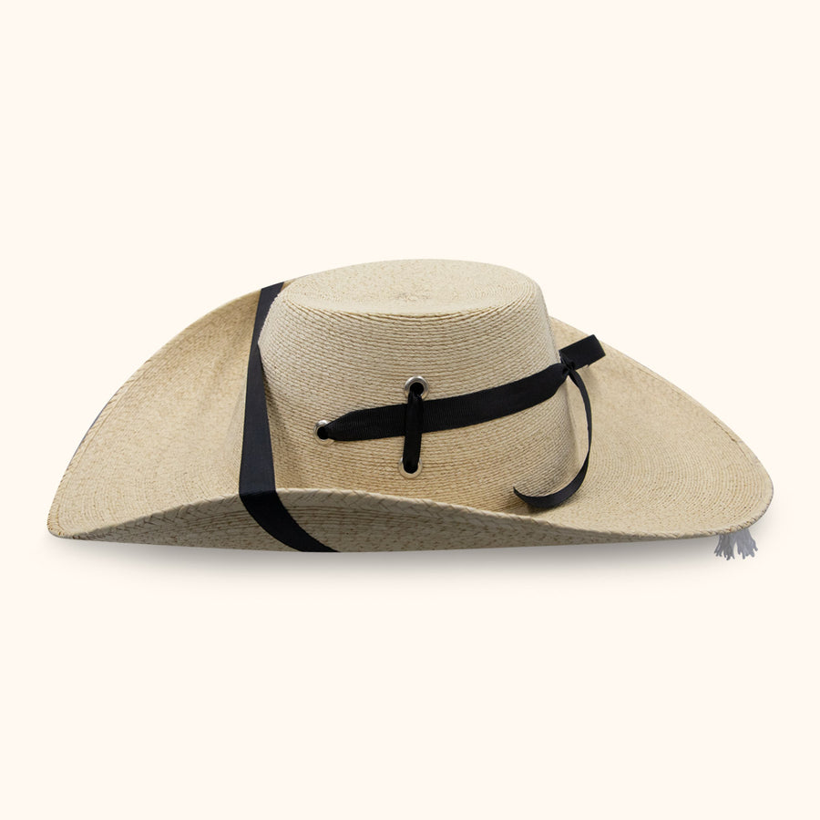 Sombrero tejido beige de perfil, con banda negra y cordón lateral