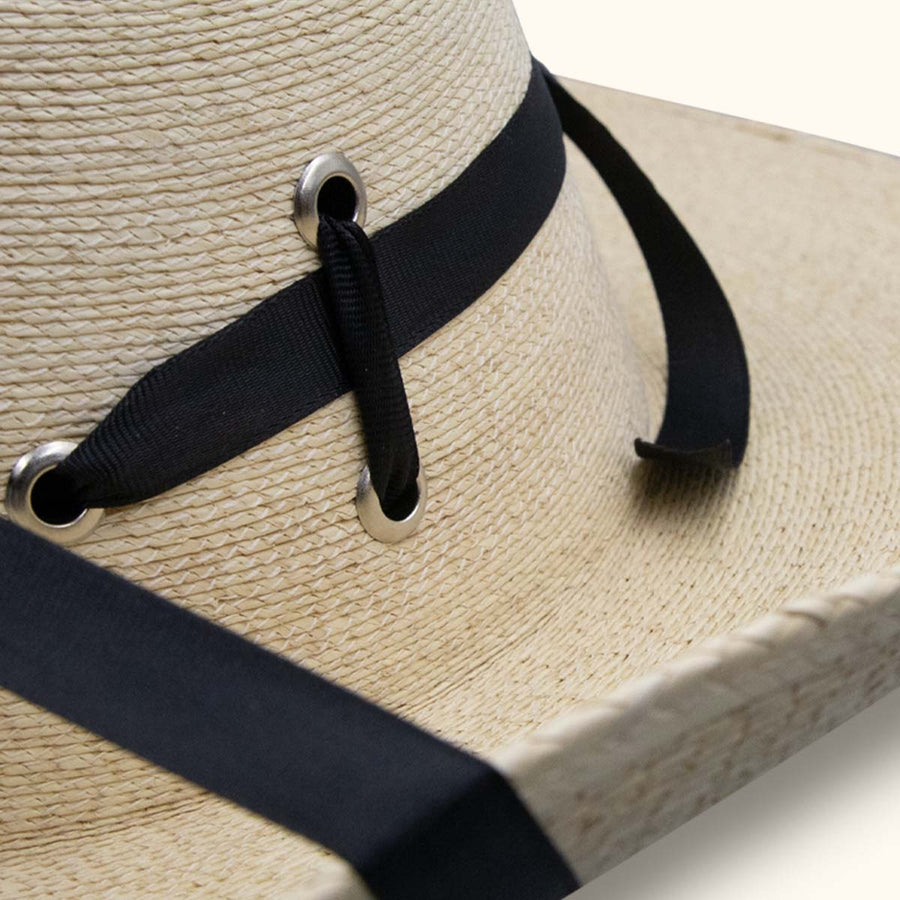 Detalle del sombrero tejido con ojales metálicos y cordón negro